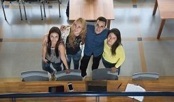 Estudiantes en la biblioteca, parados posando mirando para arriba