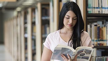 estudiante en la biblioteca mirando un libro