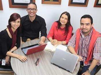 Docentes sentados en mesa redonda alrededor de computadores