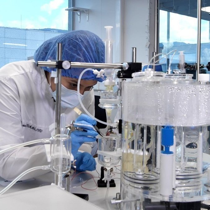 Mujer con vestuario clínico manipulando máquina de laboratorio