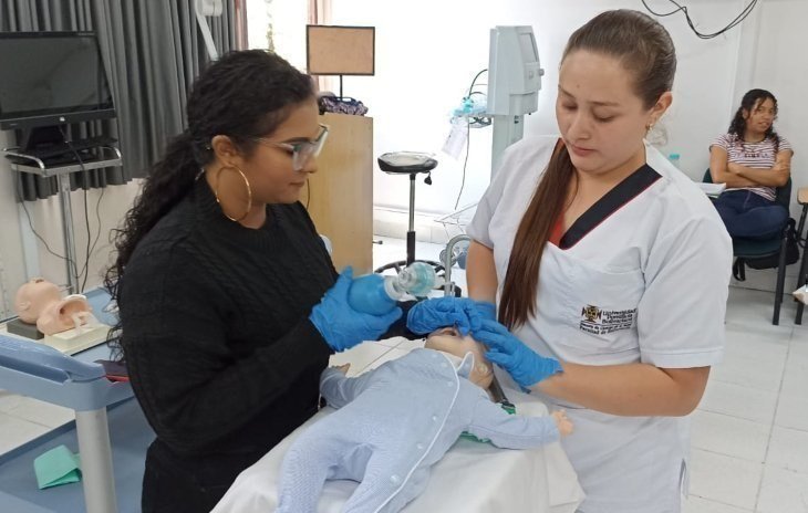 Dos estudiantes de Enfermería UPB haciendo prácticas con bebé de plástico en consultorio médico con