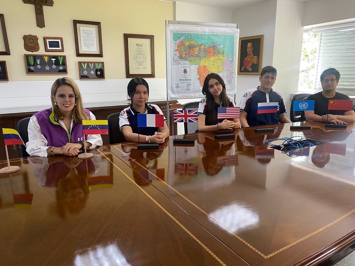 Estudiantes de colegios ubicados en una mesa con banderas de diferentes países