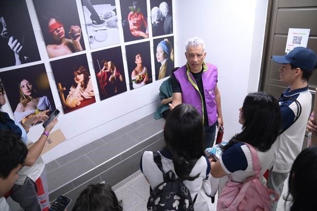 Estudiantes viendo fotografías ubicadas en una pared